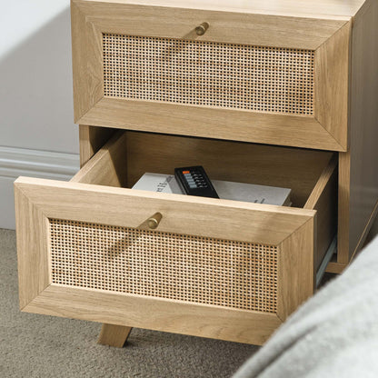 Brown oak wood two-drawer nightstand with woven cane fronts and brass knobs; bottom drawer open with remote inside.