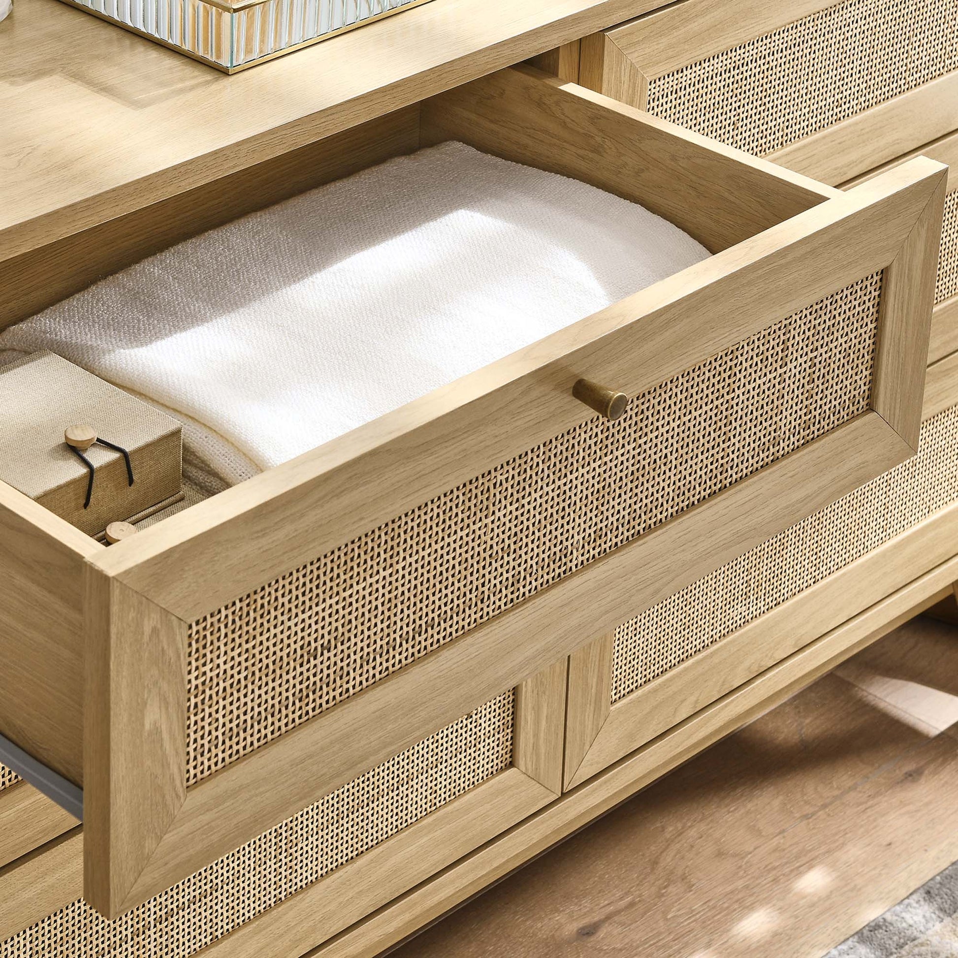Oak dresser with woven cane fronts; open top drawer reveals a white towel and a small wrapped box.
