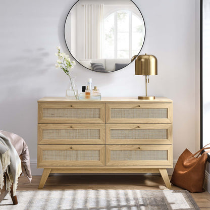 Oak dresser with six cane-front drawers & mid-century legs; brass lamp, vase & bottles on top under round mirror.