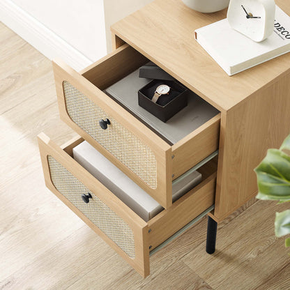 Oak nightstand with two cane-front drawers; top drawer open holds a watch box, with a clock and book on top.
