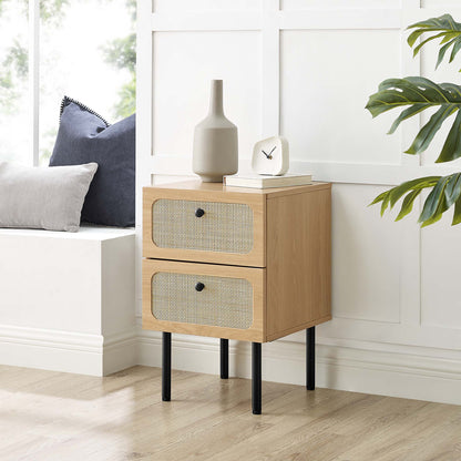 Oak wood two-drawer nightstand with woven rattan fronts on black tapered legs, decor vase, clock, books