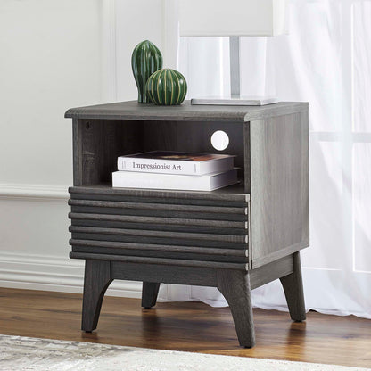Black nightstand with a slatted drawer front, open shelf, and tapered legs; green ceramic vases and a lamp on top.