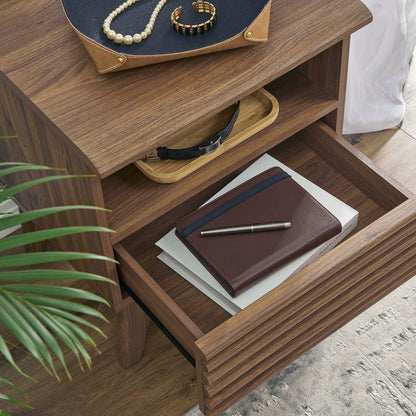Walnut wood nightstand with drawer & top tray; brown leather wallet & pen in the lower drawer, pearl jewelry on the top tray, plant nearby.