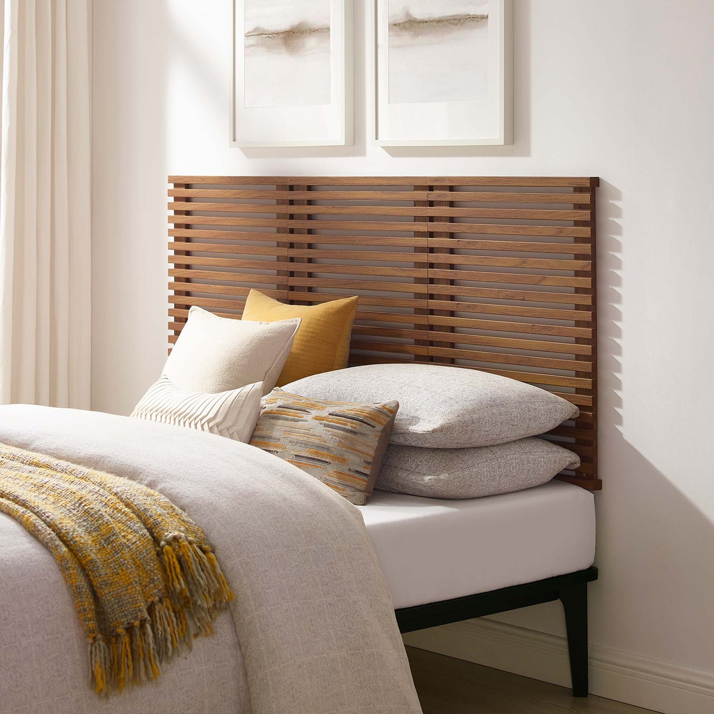 Walnut slatted wall-mounted queen headboard with cream-gray bedding, mustard throw, and layered pillows in a bright bedroom.
