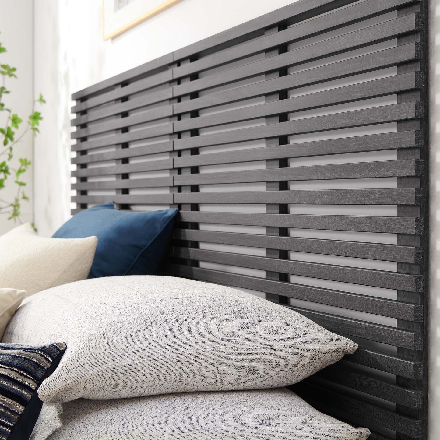 Dark charcoal slatted wooden headboard with horizontal slats; gray textured and blue pillows in a modern bedroom.