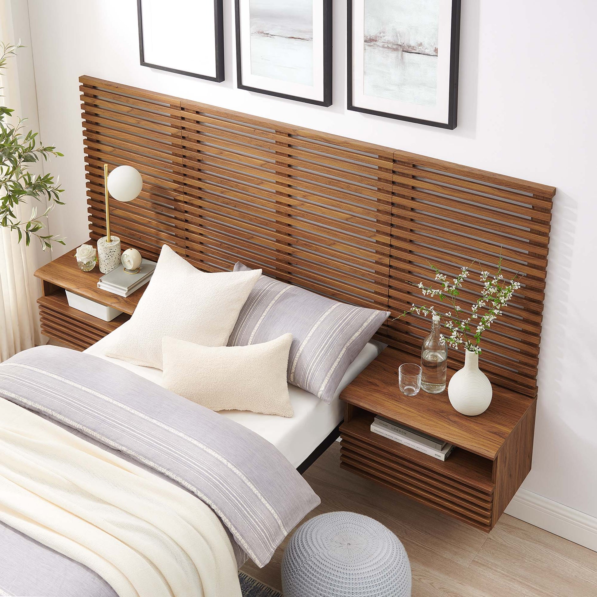 Walnut slatted headboard with built-in nightstands, bed with gray/cream bedding, vase with branches, lamp, and plant decor.