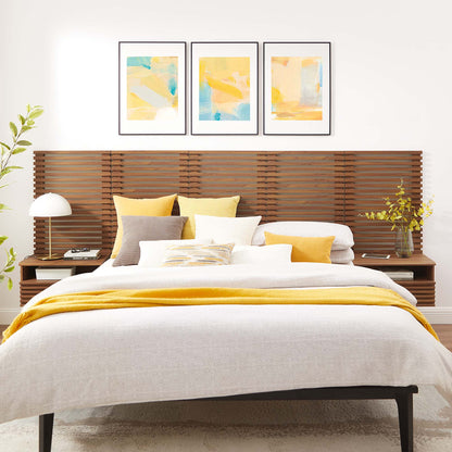 Walnut wall-mounted queen headboard with beige bedding, yellow throw and pillows; three pastel abstract prints above.