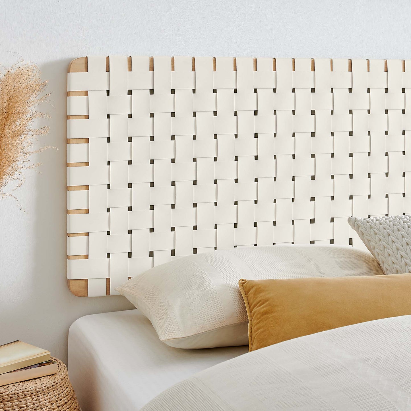 Natural beige vegan leather wall-mount headboard with white bedding, mustard pillow, & dried pampas decor in a cozy bedroom.