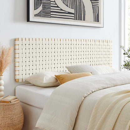 Natural beige vegan leather headboard on a white bed with cream linens; dried pampas grass vase beside bed and abstract art above.