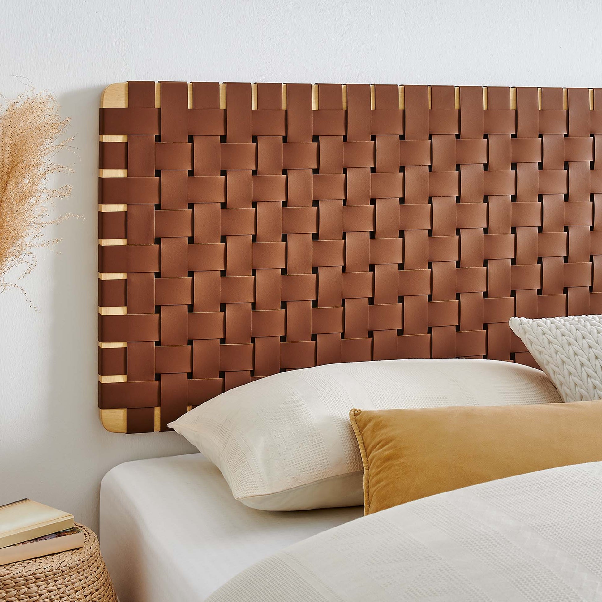 Woven brown vegan leather headboard with natural wood trim; white bedding and mustard pillow for a chic boho bedroom.