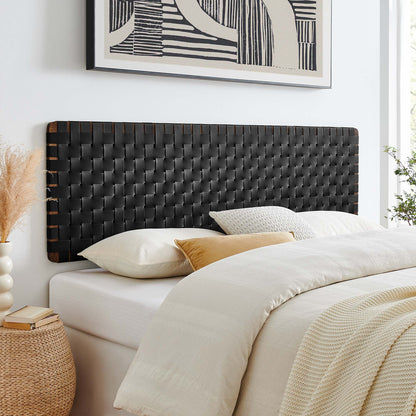Woven black wall-mount headboard (vegan leather) for a king bed; white bed with cream duvet and tan accent pillow; wicker nightstand and abstract art above.