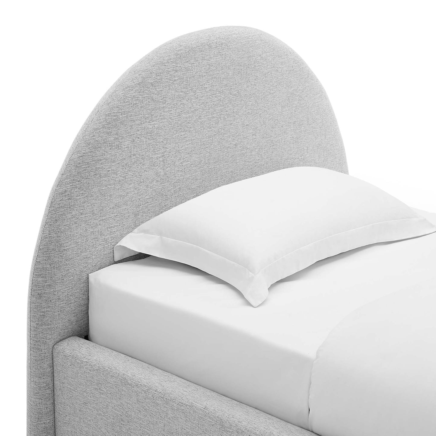Grey curved upholstered bed with white bedding and a pillow.