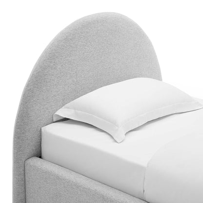 Grey curved upholstered bed with white bedding and a pillow.