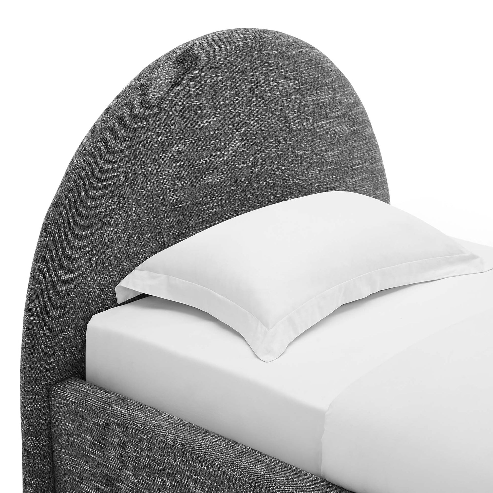 Dark gray fabric upholstered bed with a large curved arched headboard, white sheets and a white pillow.