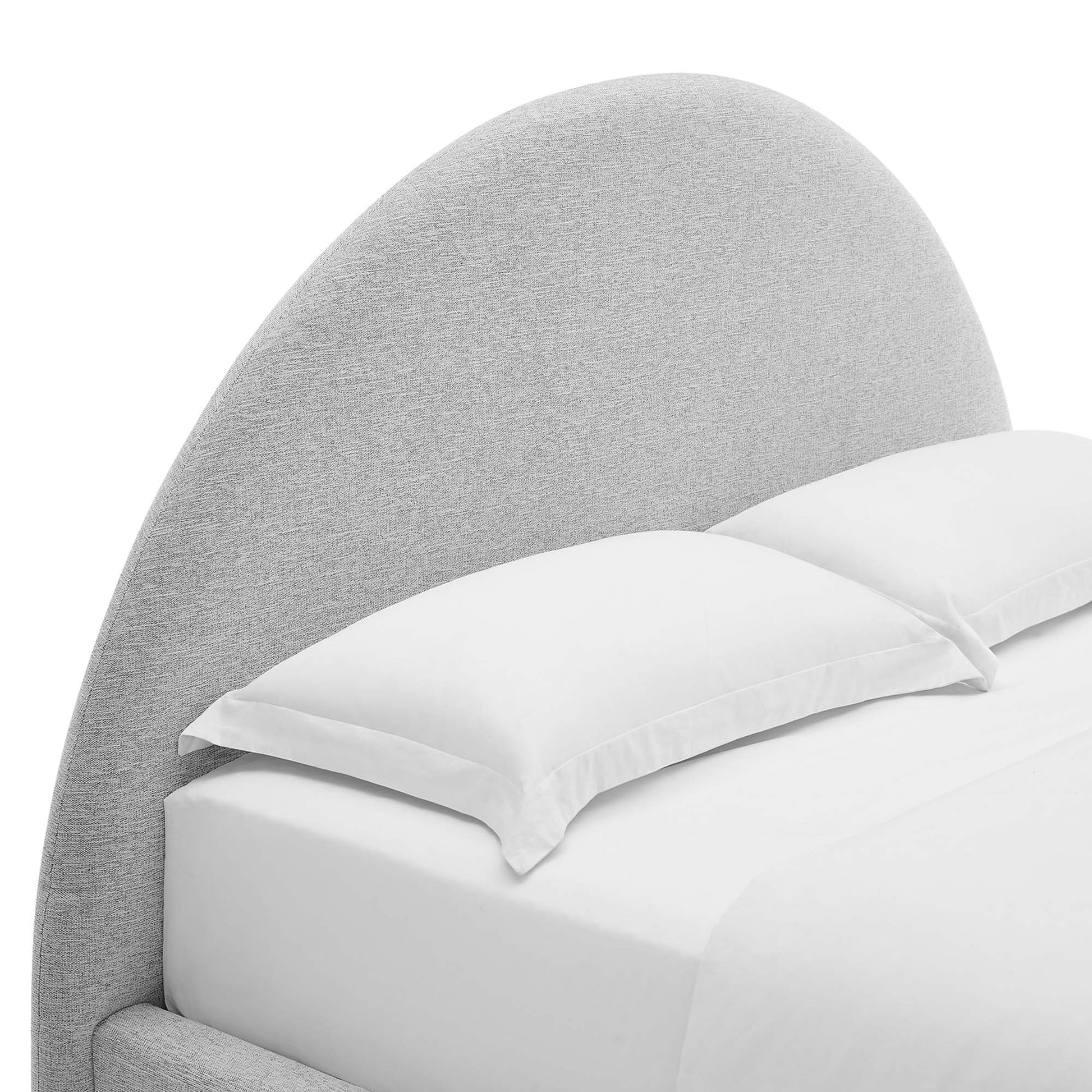 Light gray curved fabric headboard with white sheets and pillows on a bed