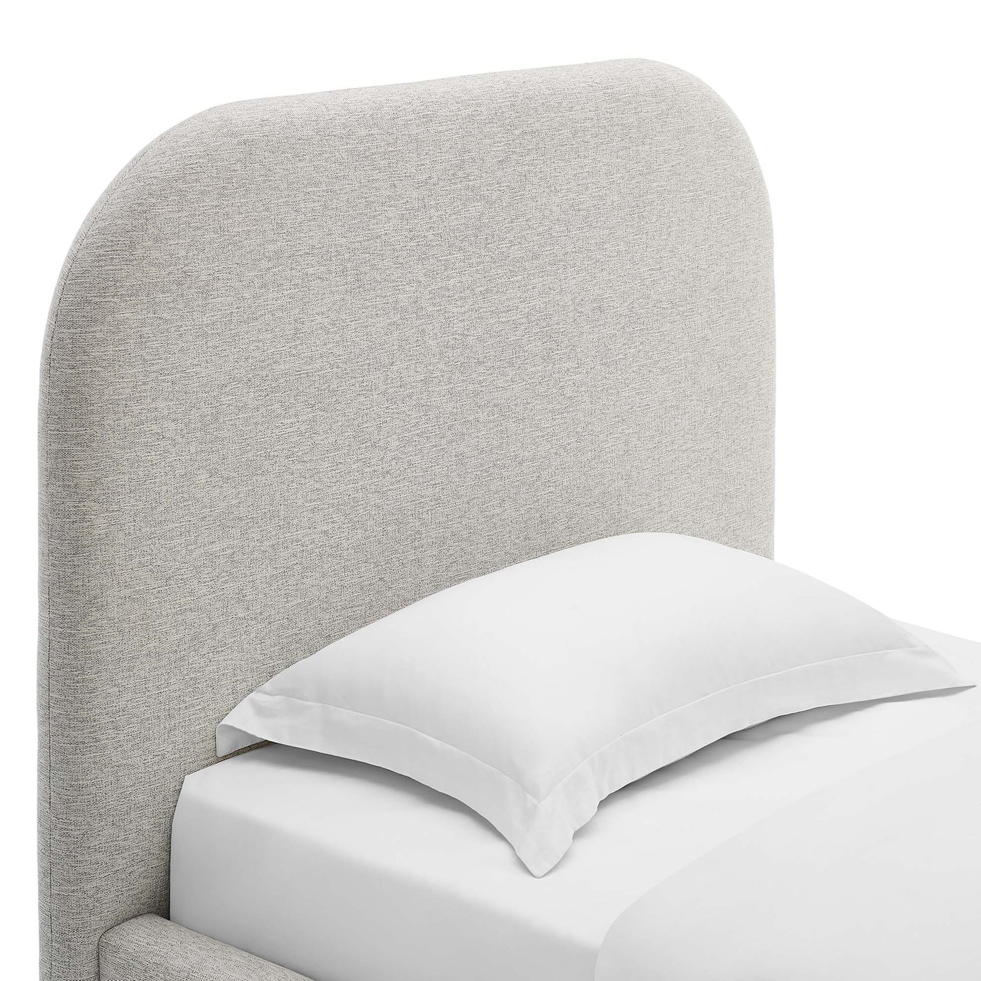 Light gray fabric upholstered curved headboard bed with white pillow and sheets.