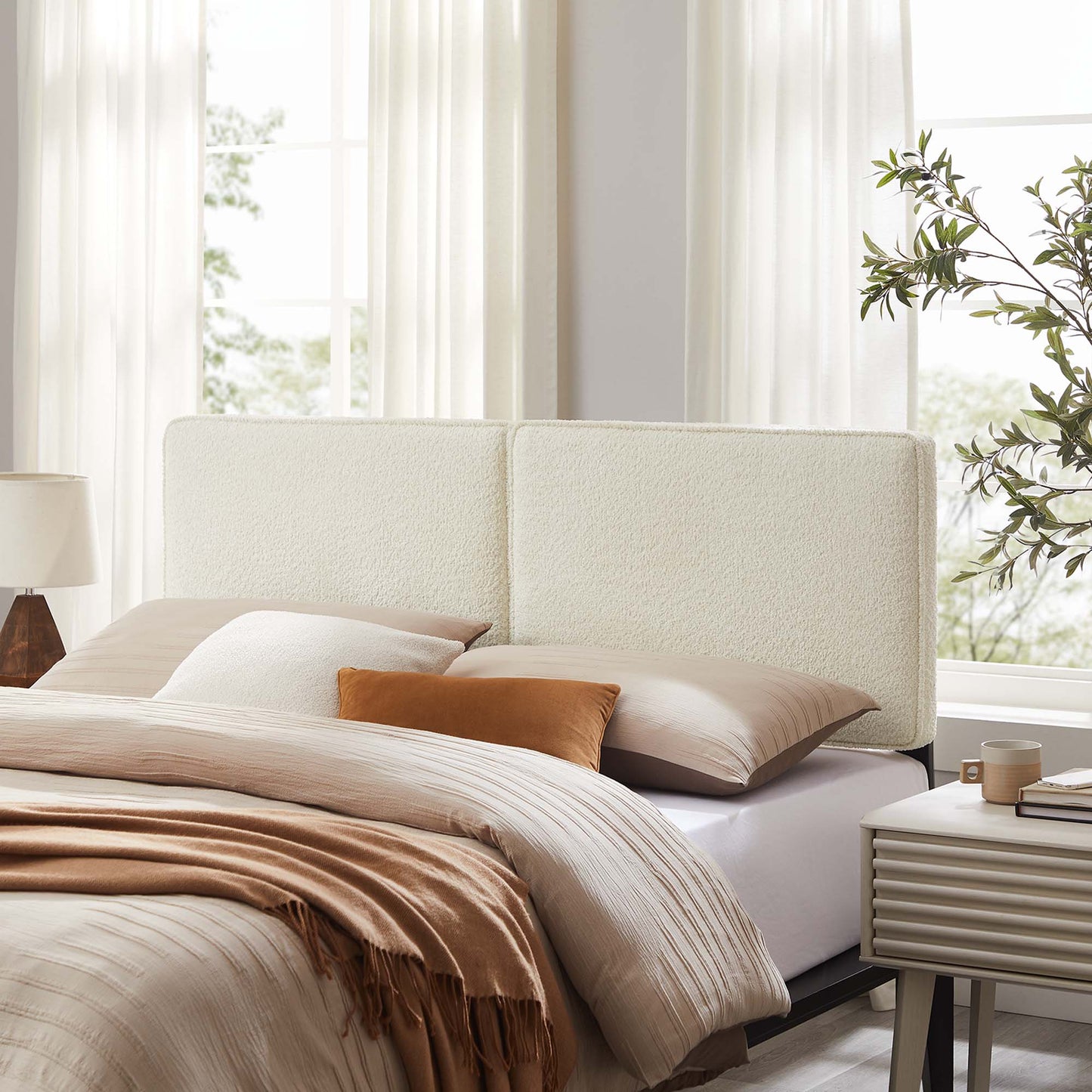 Brown boucle fabric queen headboard in a contemporary bedroom with white curtains; textured upholstery.