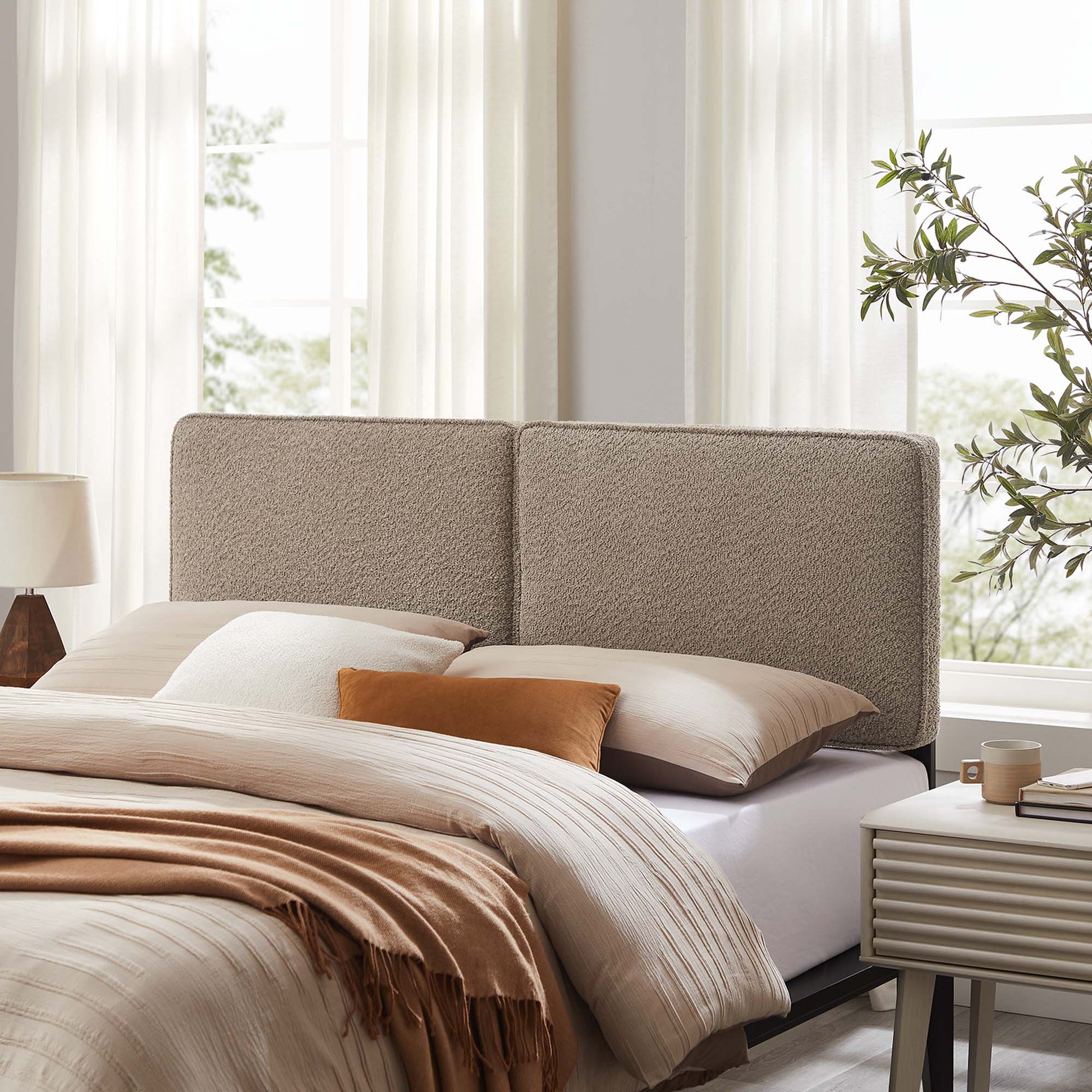 Beige two-panel upholstered headboard in a sunlit modern bedroom, with oat bedding, tan throw, and matching pillows.