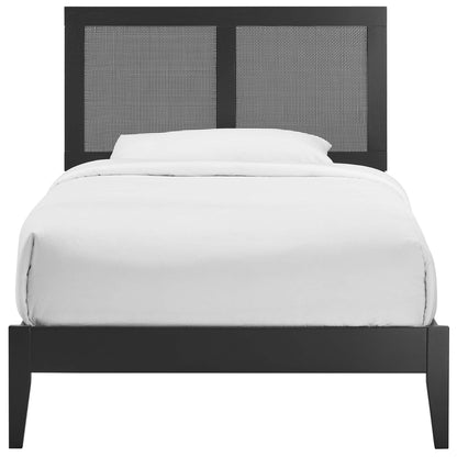Black platform bed frame with two woven cane headboard panels and white bedding.