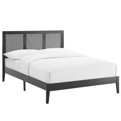 Black full-size platform bed with a rattan and wood frame, slim legs, and white bedding.