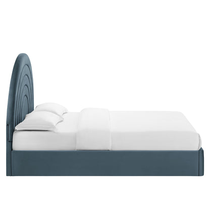 Blue upholstered platform bed with a circular stacked-arch headboard and white bedding.