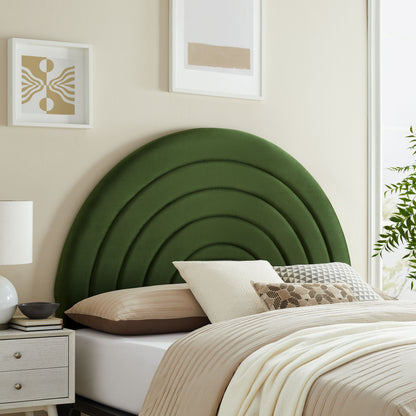 Emerald green arched upholstered headboard with concentric curves; beige bedding, decorative pillows, nightstand, framed art.