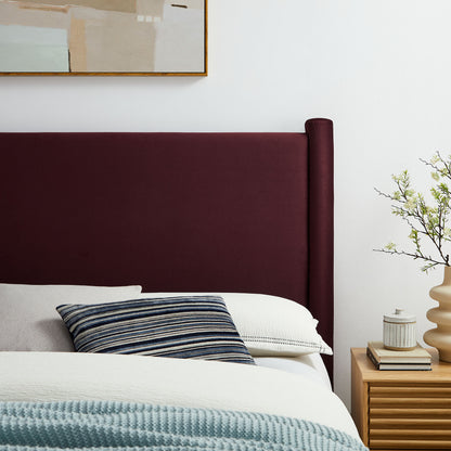 Purple upholstered full headboard with white bedding, blue striped pillow, light blue throw; wood nightstand with plant.
