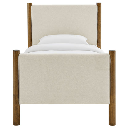 Beige fabric upholstered four-poster bed with walnut posts and white bedding.