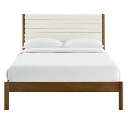 Walnut wooden platform bed with a cream channel-tufted boucle headboard and white bedding.