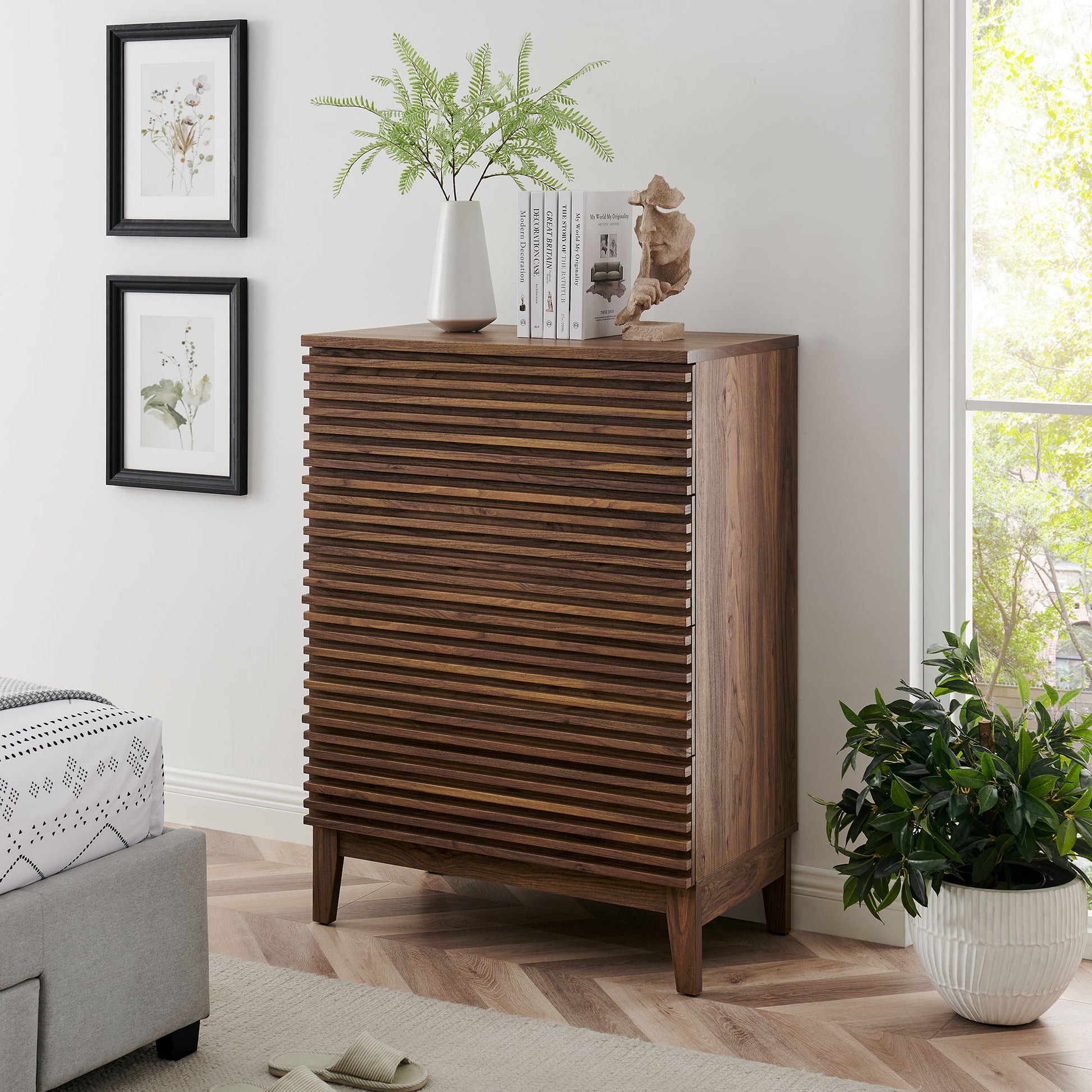 Walnut 4-drawer chest with tapered legs in a bright living room, topped with a fern, books, and a small statue.