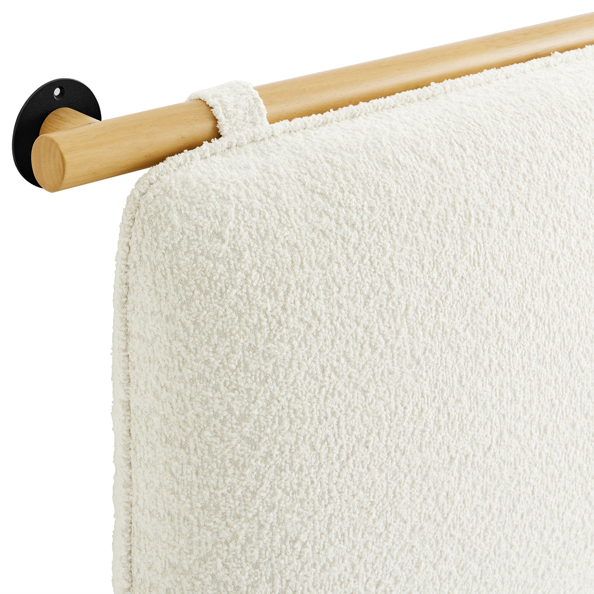 Cream textured towel on natural wood towel bar with black circular wall mount.