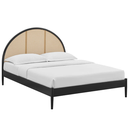 Black arched rattan cane platform bed with a curved headboard and white bedding.