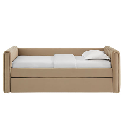 Taupe upholstered twin daybed with padded arms and pull-out trundle, dressed in white sheets and pillow.