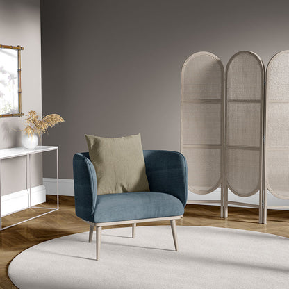 Blue upholstered armchair with light wood legs and beige cushion, in a modern living room with a woven room divider and rug.
