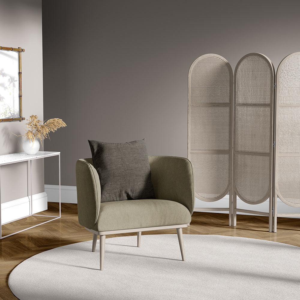 Olive-green mid-century armchair with gray cushion in a modern living room, circular beige rug and woven room divider.