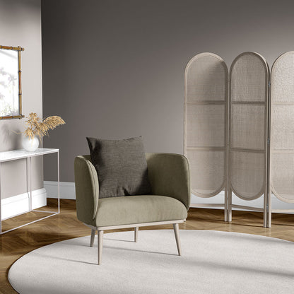 Olive-green mid-century armchair with gray cushion in a modern living room, circular beige rug and woven room divider.