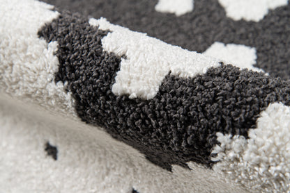 Close-up of a black and white shag rug with plush loops and bold geometric pattern.