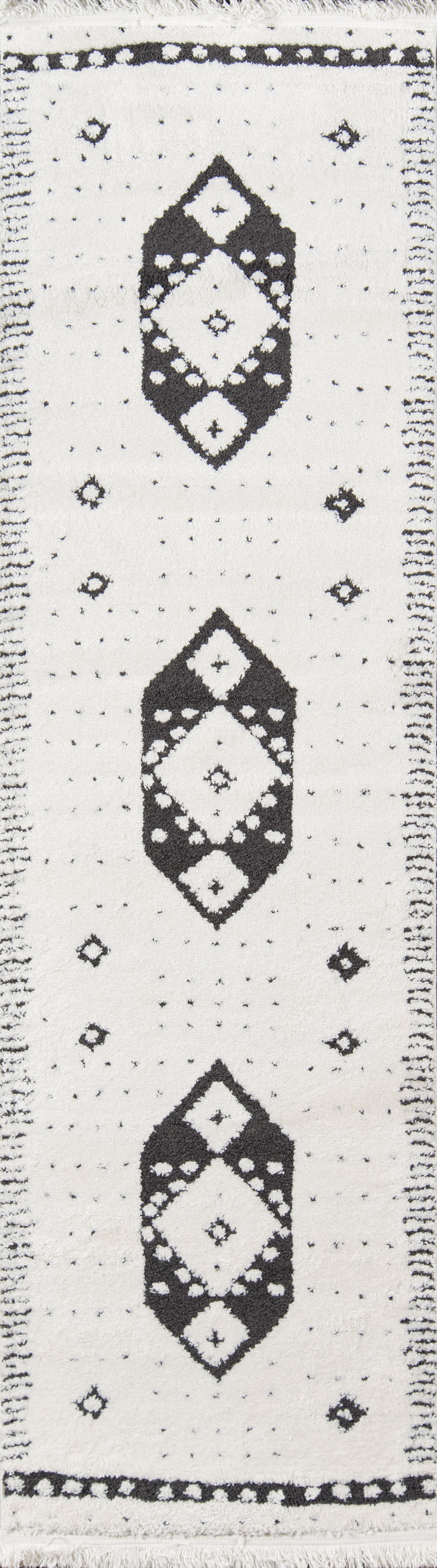 White rug with black geometric diamond motifs, dotted field, bordered by small diamonds and fringe ends.