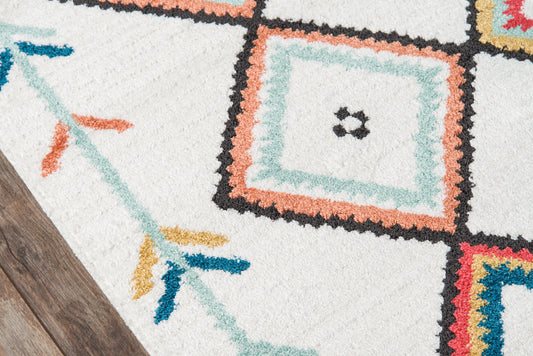 Shaggy white area rug with multicolored geometric squares in teal, peach, black & coral on a wooden floor.