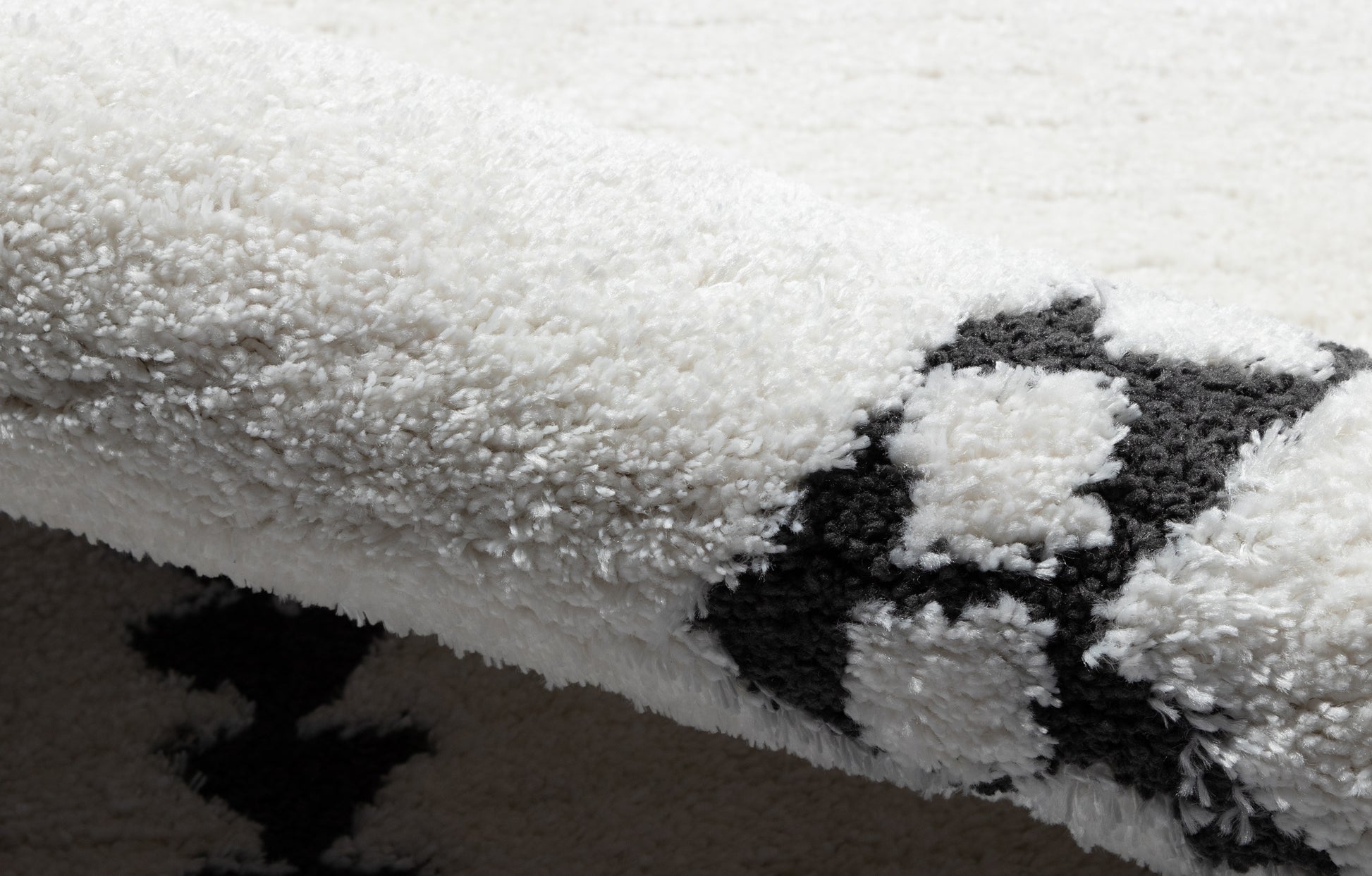 White shag rug with bold black geometric pattern, thick fluffy pile and soft, plush texture.