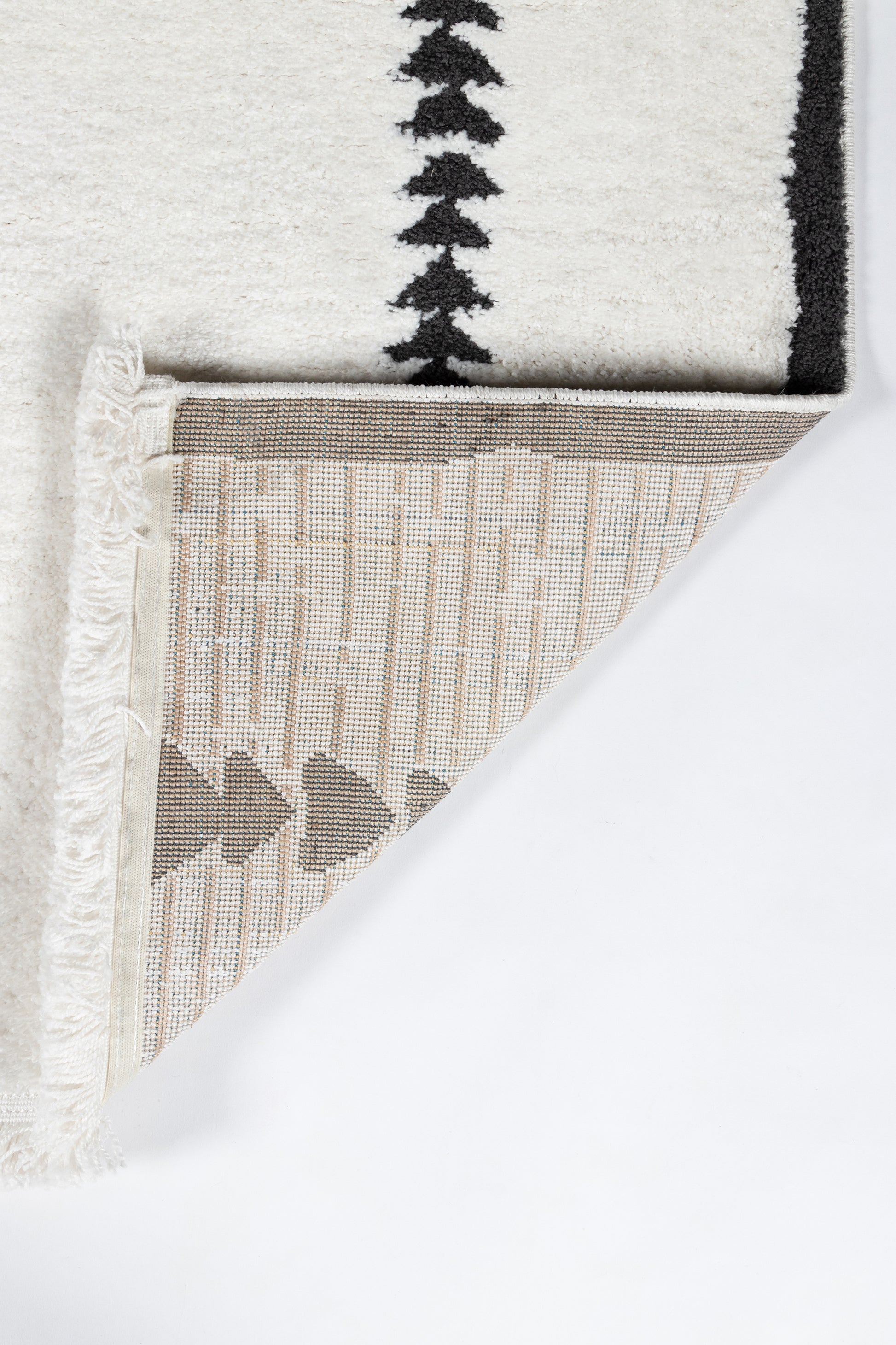 Ivory rug with black border pattern; folded corner reveals beige woven underside with geometric triangles; fringed trim.