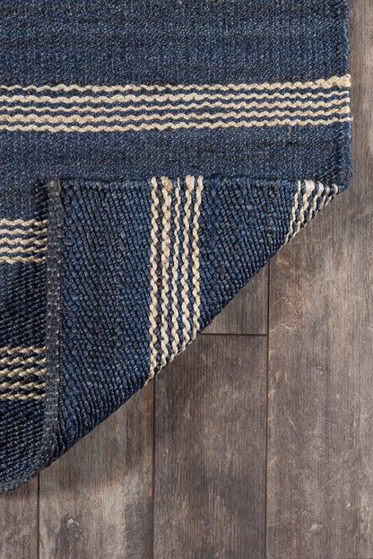 Navy blue flatweave rug with natural beige stripes; folded corner on wood floor.