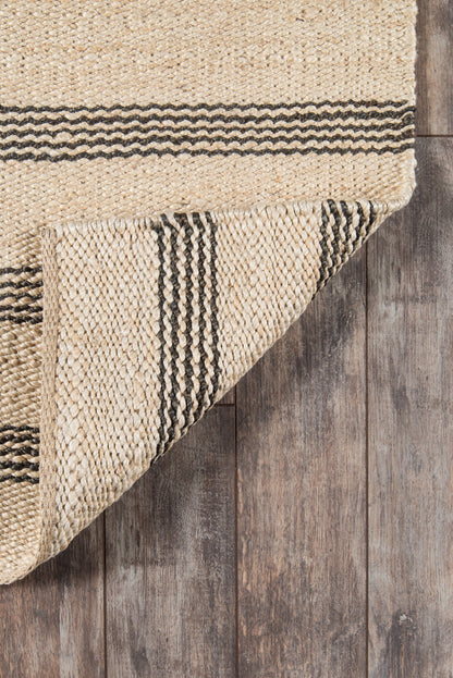 Natural beige jute area rug with black striped border, folded corner on rustic wood floor.