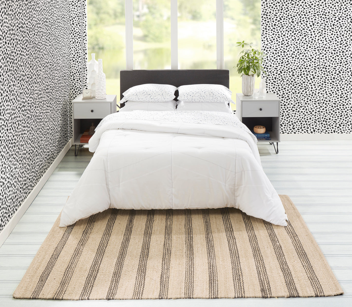 Beige striped runner rug on a bedroom floor beside a bed with a dark headboard, gray nightstands, dotted black-and-white wallpaper, and a potted plant.