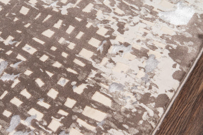 Brown geometric area rug with beige and cream squares and gray accents, bound edge on a wooden floor.