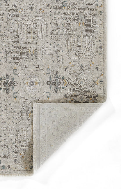 Gray vintage rug with a distressed floral/geometric pattern, subtle blue & yellow accents; corner folded to reveal reverse weaving.