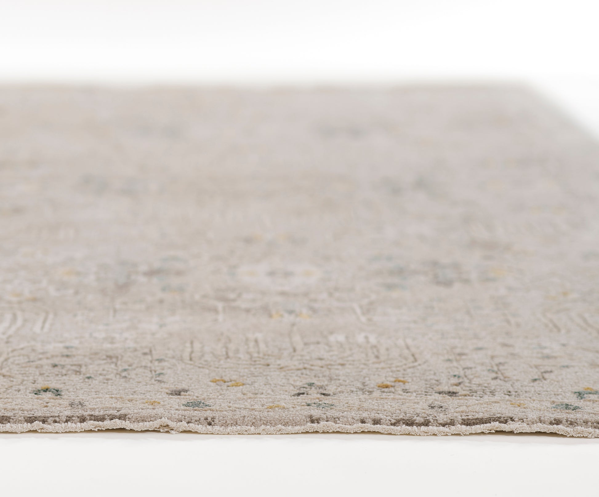 Gray woven rug with subtle geometric pattern in muted beige and green; edge visible.