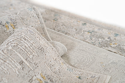 Grey-beige traditional patterned area rug with blue and pale yellow accents; plush pile and rolled edge.