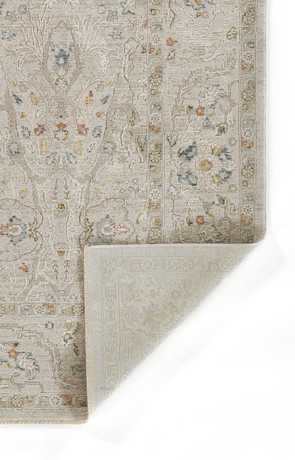 Beige oriental rug with subtle floral pattern, blue and pink accents, ornate border, folded corner reveal.