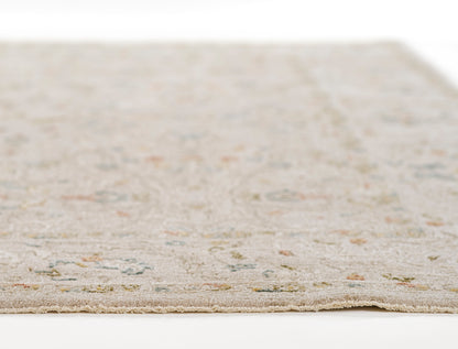 Beige rectangular rug with subtle pastel floral motifs in blue, green and pink; fringed edges, soft tufted texture.